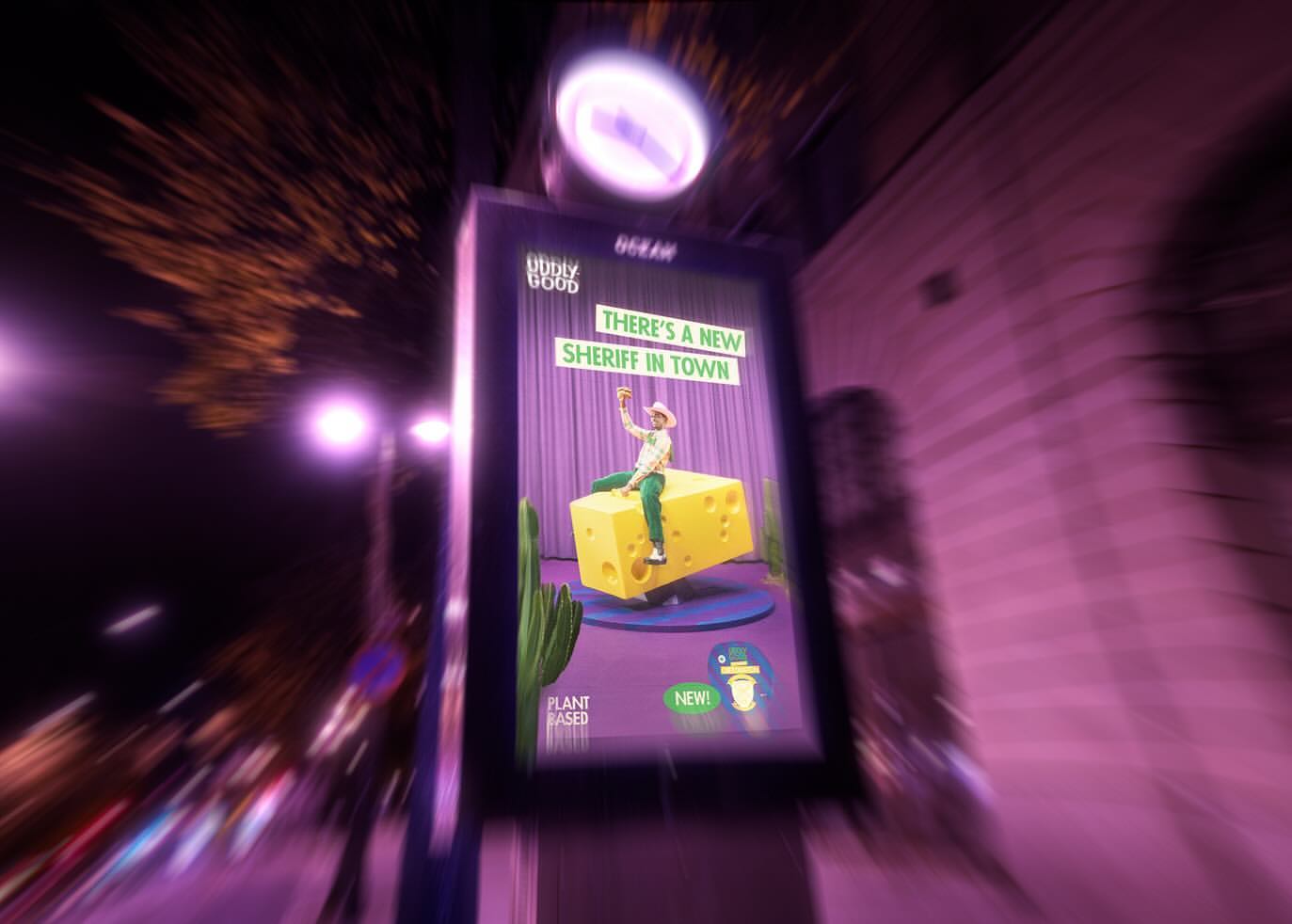 Eye-level shot of an outdoor advertising display at night, featuring a playful cartoon image of a man on a block of cheese.