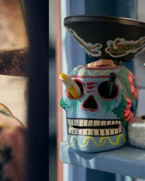 Blue painted skull ceramic container with pens in eye sockets sitting on a shelf by photographer Richard Wadey