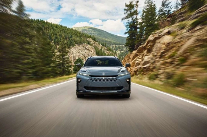 Grey car driving on asphalt road with mountain range and forest background under blue sky with clouds, motion blur effect.