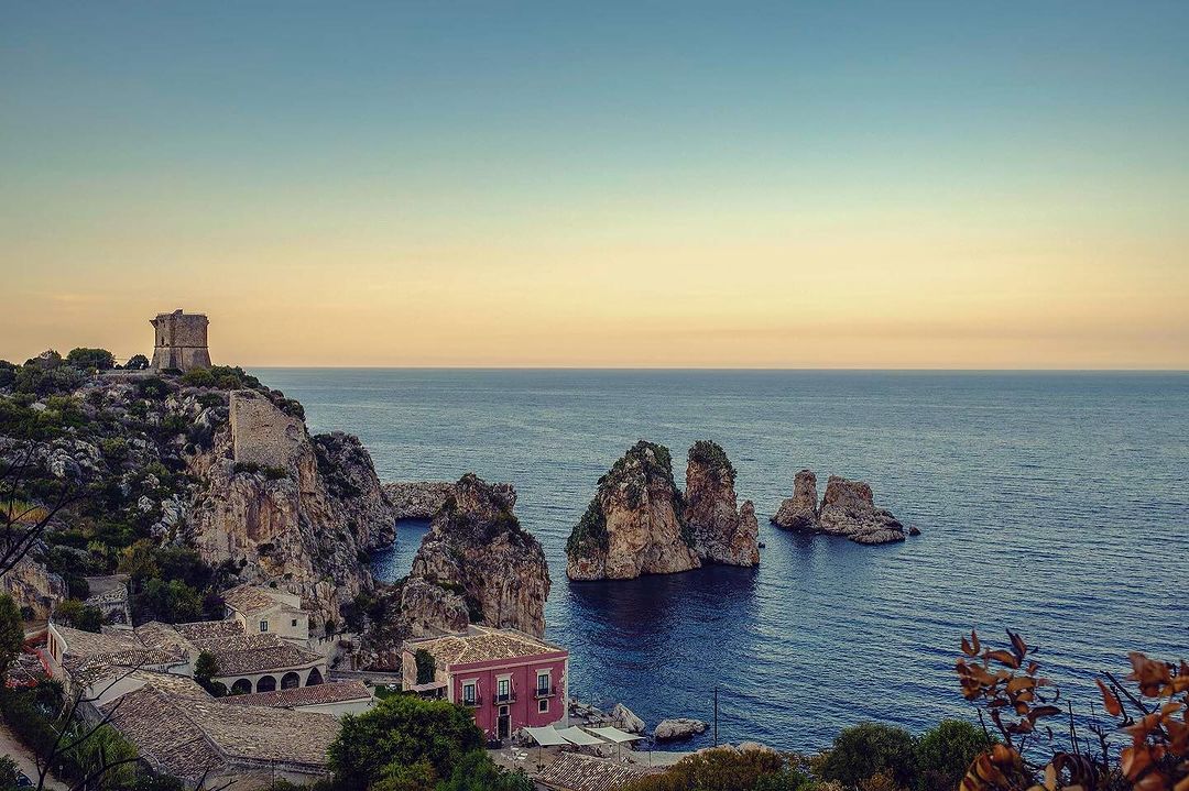 Seascape view of Scopello coastline, Sicily, with the Tonnara di Scopello tower perched on cliffs overlooking the Tyrrhenian Sea and stack rocks.