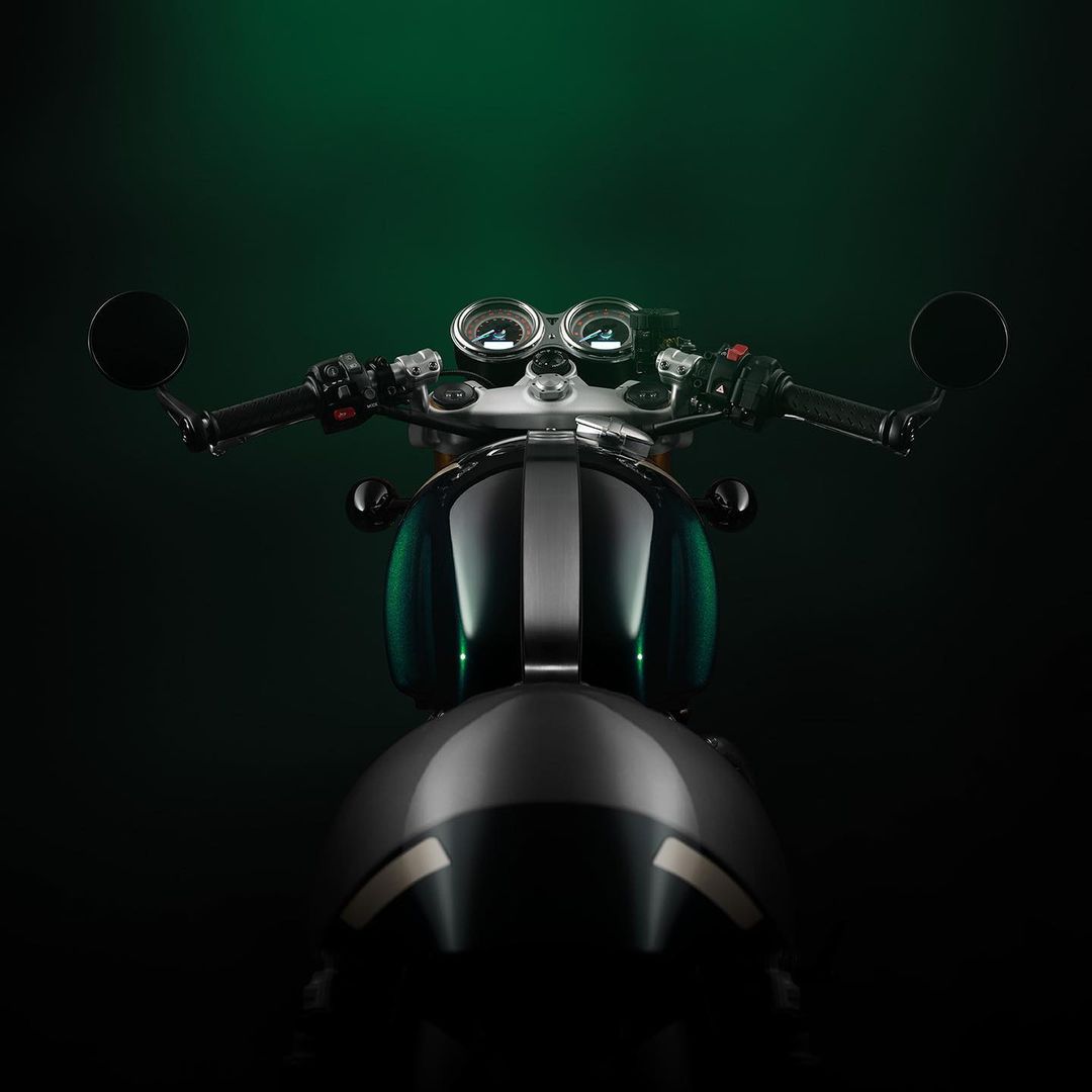 Front view of a sleek, dark grey and green motorcycle against a gradient dark green background, focusing on the handlebars and fuel tank.