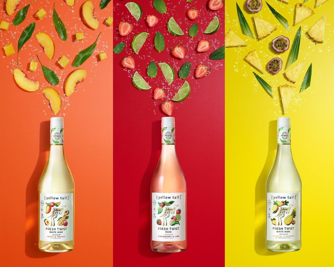 Three bottles of Yellow Tail Fresh Twist wine, each paired with matching fruit ingredients on a color-blocked orange, red, and yellow background.