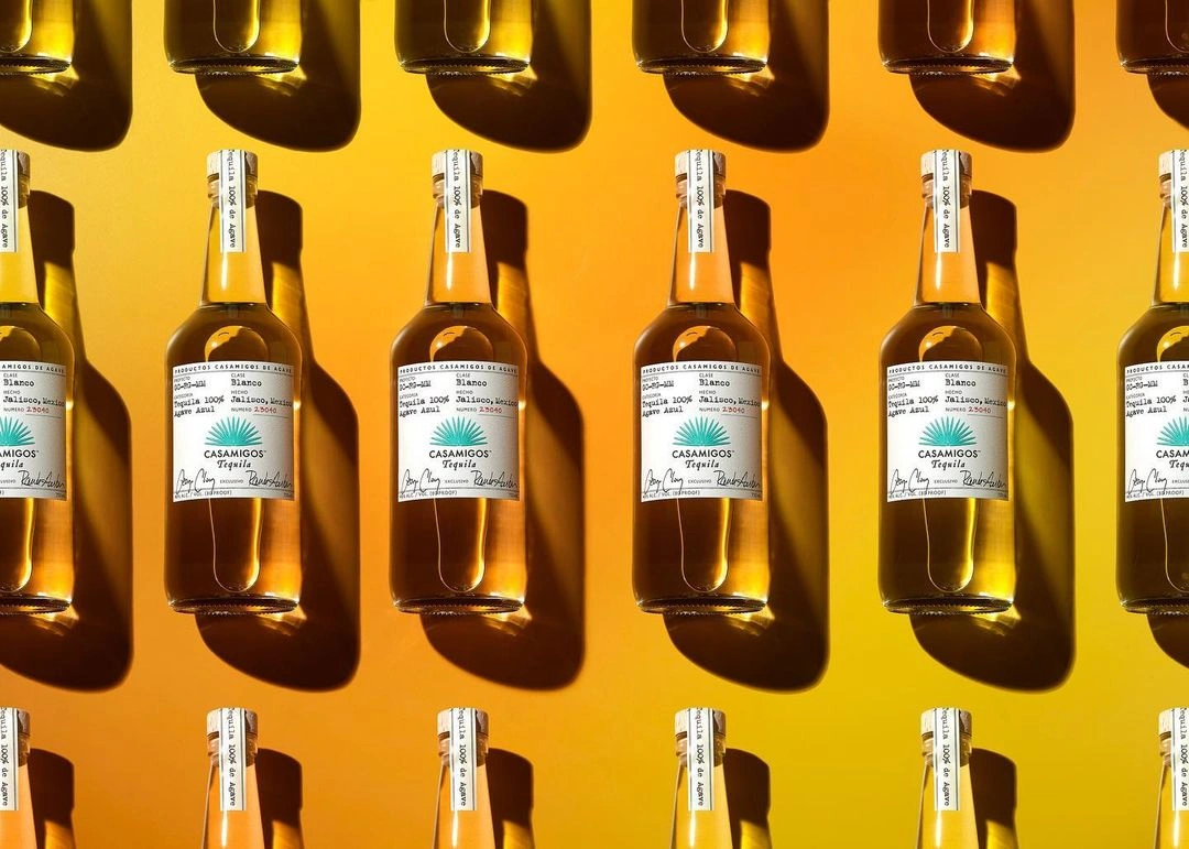 Repeated pattern of tequila bottles against a vibrant gradient orange background with cast shadows