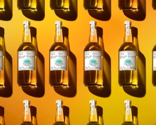 A repeating grid pattern of amber tequila bottles against a vibrant yellow gradient background with sharp directional shadows.