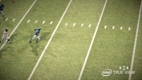 High-angle aerial view of a football player running across a green turf field marked with white yard lines.