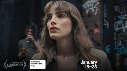 Close-up of a woman with long brown hair, light complexion, wearing a collared shirt. A man stands in the blurred background. Sundance Film Festival logo.