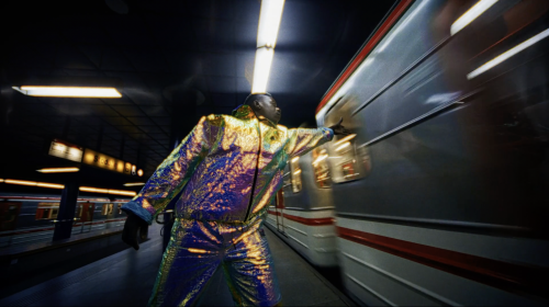 A person in a iridescent tracksuit is reaching out to touch a subway train speeding along the tracks at an underground station.
