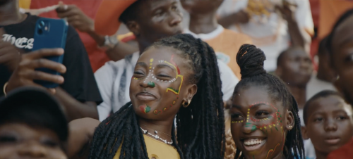Enthusiastic spectators with face paint in a stadium setting, showcasing diverse expressions and vibrant fan culture.