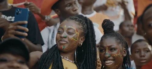 Enthusiastic spectators with face paint in a stadium setting, showcasing diverse expressions and vibrant fan culture.