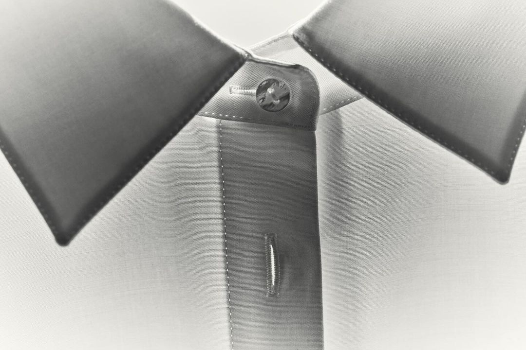 Close-up of a white dress shirt with gray collar, focused on the buttoned collar and top of the button placket.