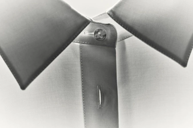 Close-up of a white dress shirt with gray collar, focused on the buttoned collar and top of the button placket.