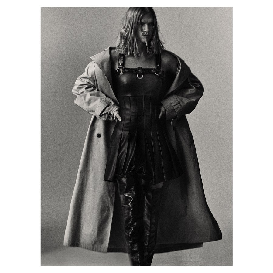 Model wearing a pleated leather dress, harness, and trench coat by Alistair Taylor-Young