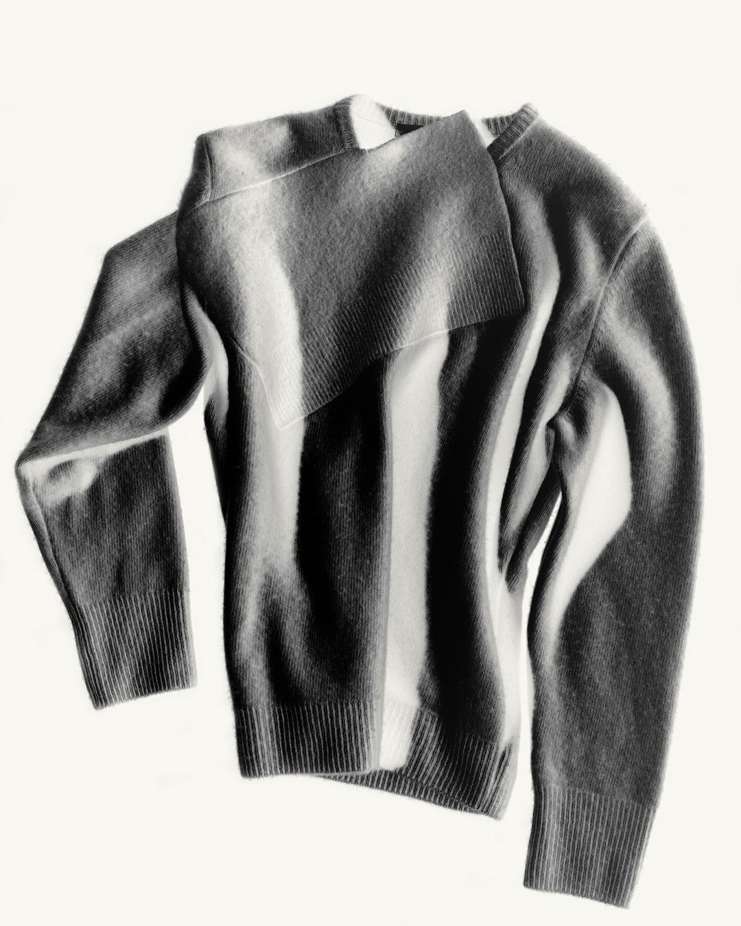 Folded knit sweater with overlapping layered panel against a plain white background