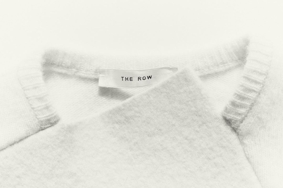 Close-up of a white wool sweater featuring a brand label; showcases details of the soft texture and minimalist design.