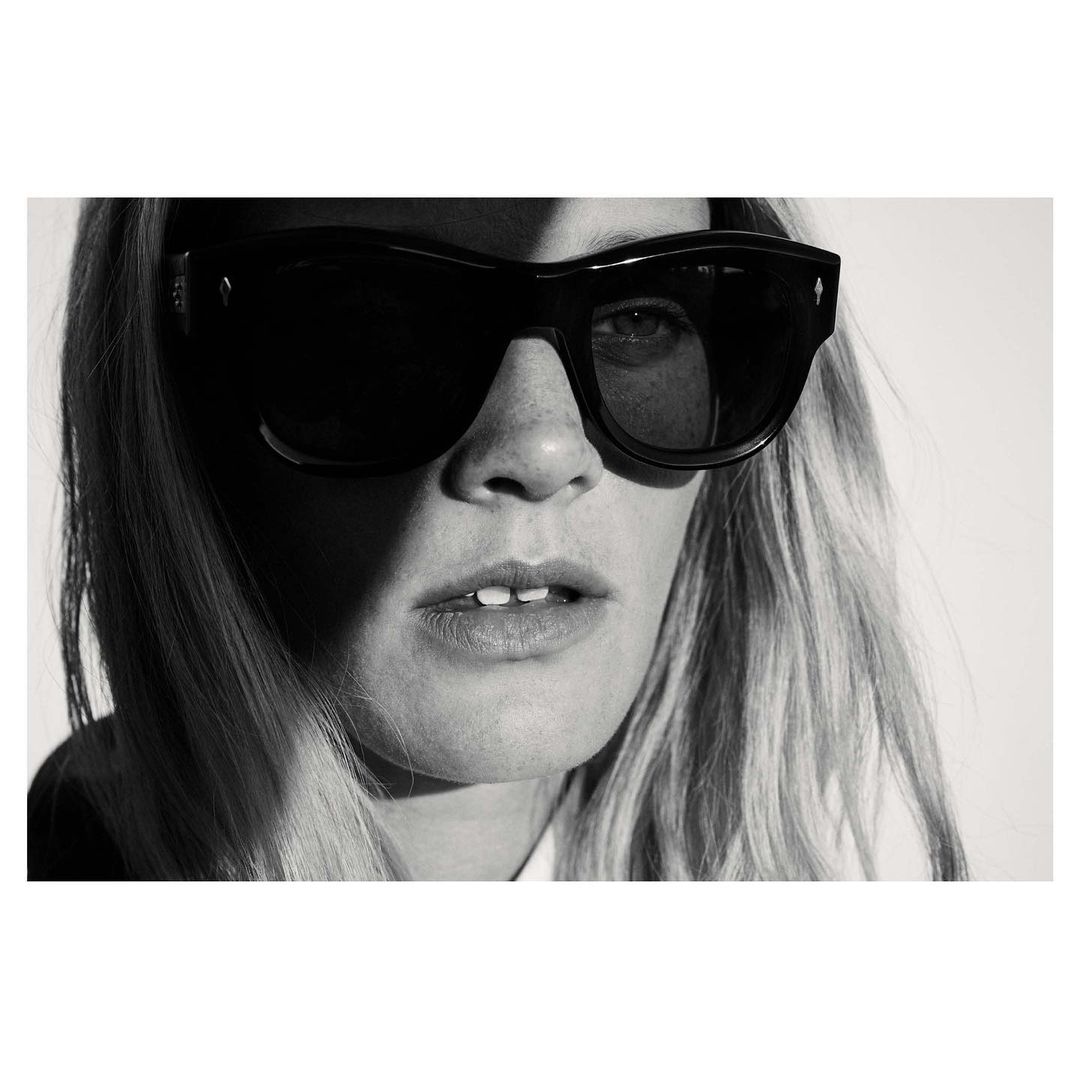 Close-up black and white portrait of a woman wearing thick black sunglasses and light-coloured hair.