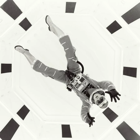 Monochrome portrait of a person in a futuristic spacesuit suspended in an octagonal corridor captured by Alistair Taylor-Young.