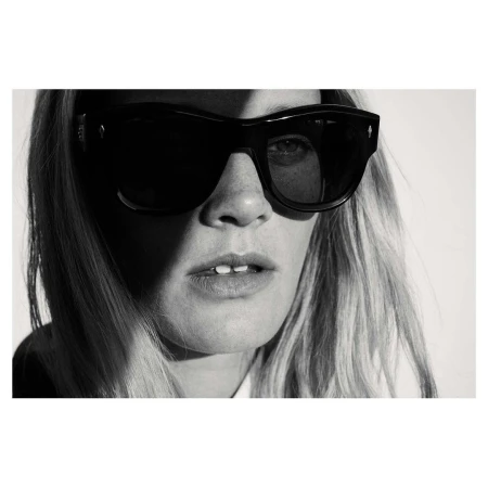 Close-up black and white portrait of a woman wearing thick black sunglasses and light-coloured hair.