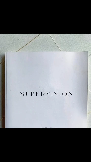 A white softcover book titled 'Supervision' lies on a white surface, shot in soft, natural lighting.