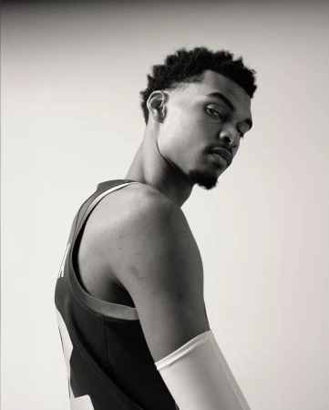 Portrait of a young Black male athlete wearing a jersey and arm sleeve against a plain white background.