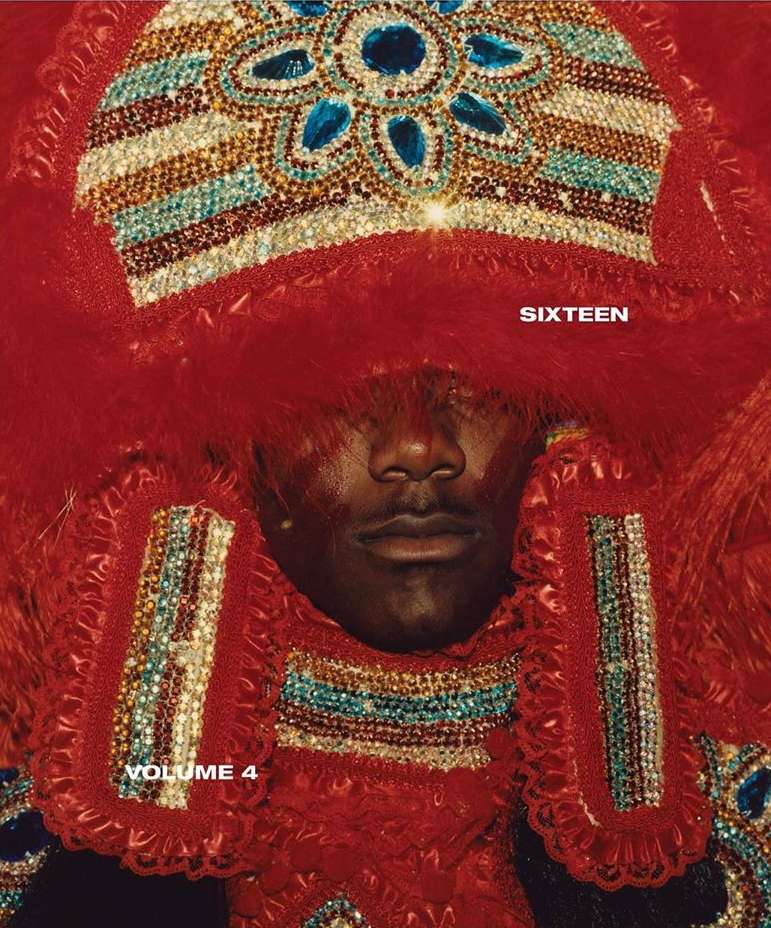 Close-up of a person wearing an ornate, colorful, red and blue beaded and feathered headdress, adorned with jewelry and embellishments.