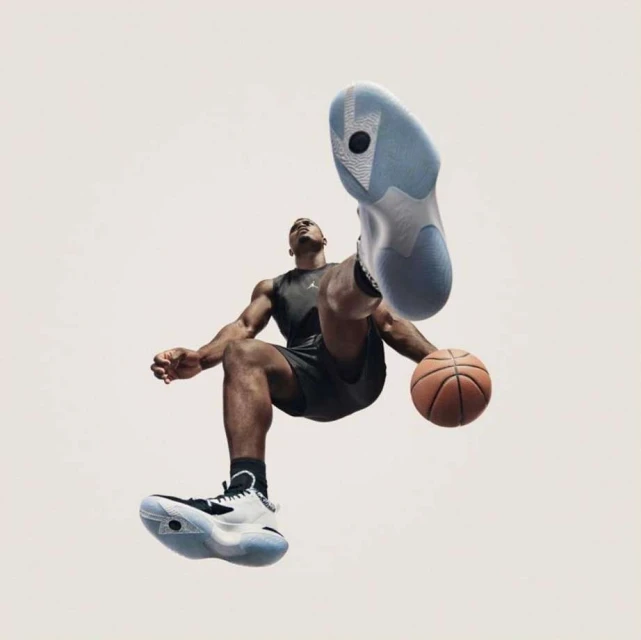 Athlete in black activewear leaps with a basketball, highlighting black, white, and light blue athletic shoes against a white background.