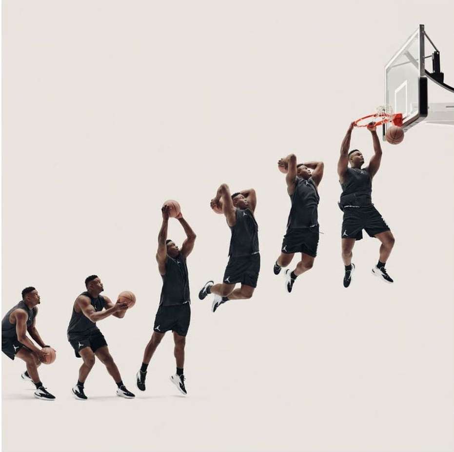 Sequence shot of an adult male basketball player in sportswear performing a slam dunk against a bright neutral studio background.