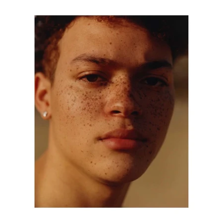 Close-up portrait of a young man with freckles and dark curly hair by photographer Anthony Blasko