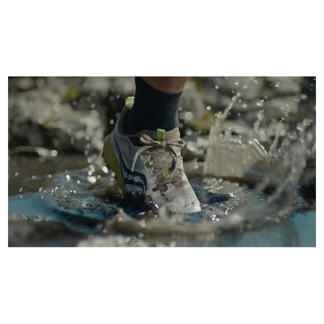 Close-up of a Saucony running shoe splashing through a puddle, showcasing its design and water resistance during outdoor activity.