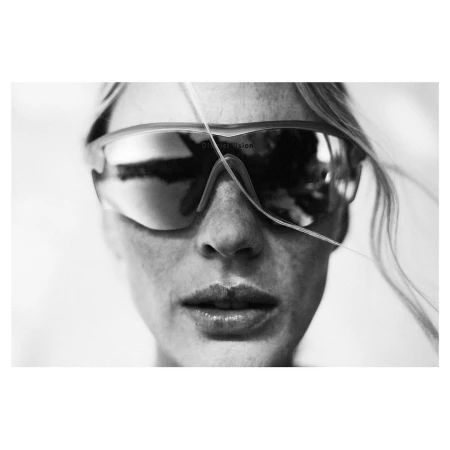 Close-up monochrome portrait of a person wearing large reflective sports sunglasses with a single strand of hair crossing the face