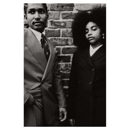 Black and white portrait of an African American couple in suits standing against a brick wall, exuding vintage fashion and style.