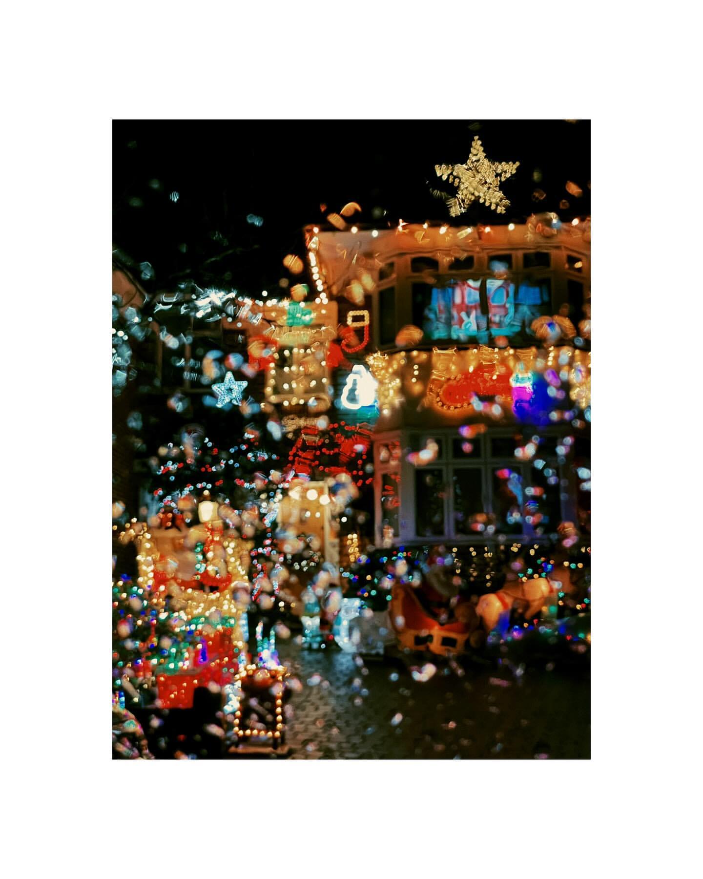 A house exterior is decorated with Christmas lights, including a star on the roof, creating a festive and illuminated nighttime scene.