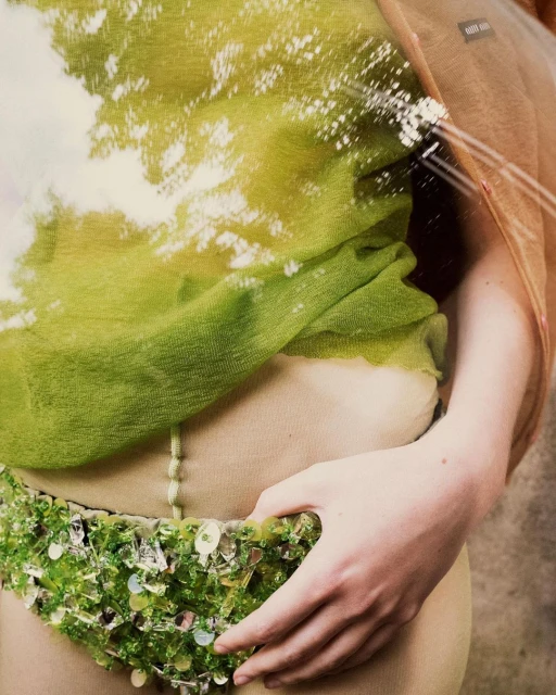 Woman in beaded belt and sheer top, filtered with tree branch, cloud, and sky overlay creating an ethereal and artistic effect.