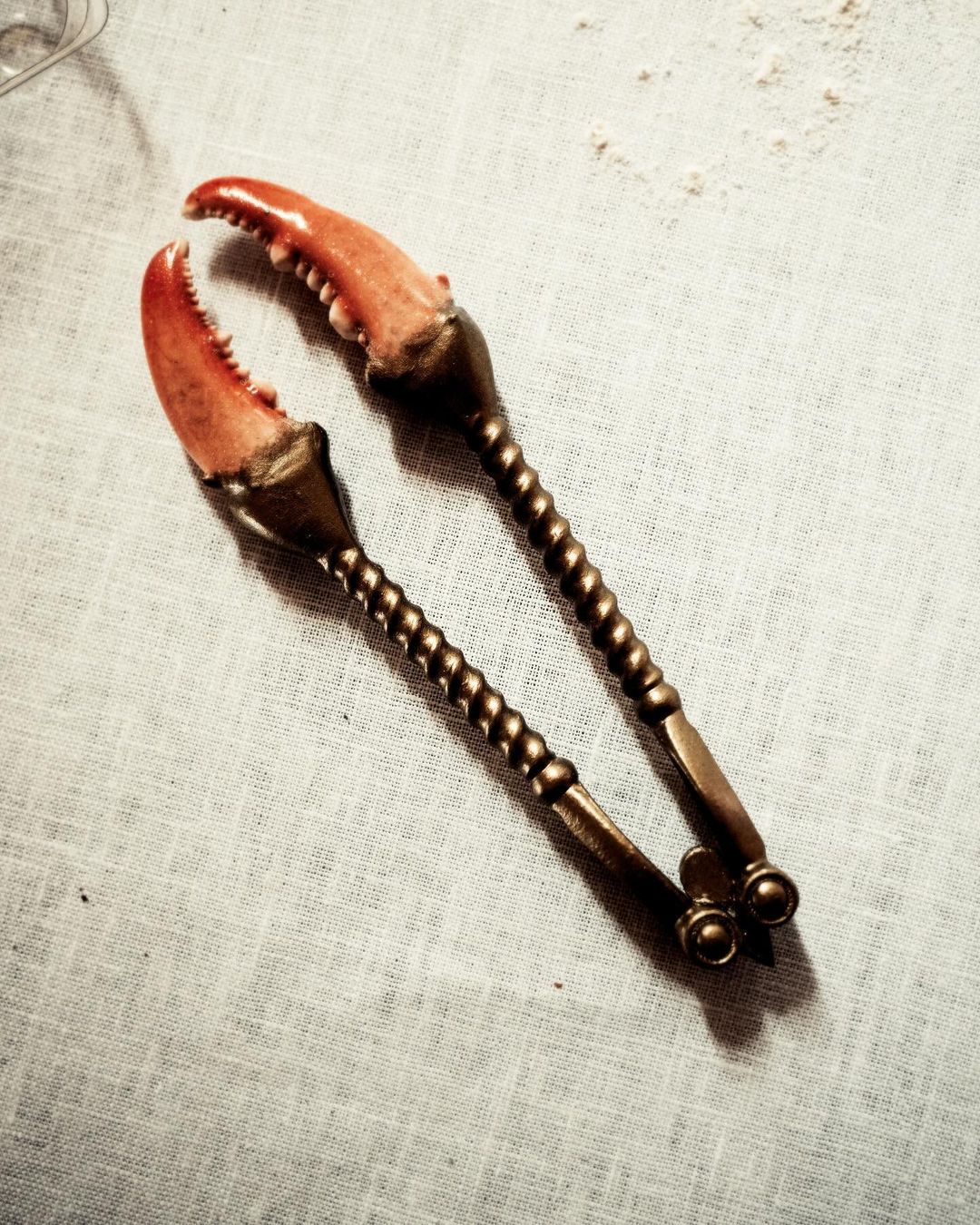 Macro shot of antique silver crab crackers on white linen, food and beverage, kitchen utensils. Perfect for food blogs and culinary websites.