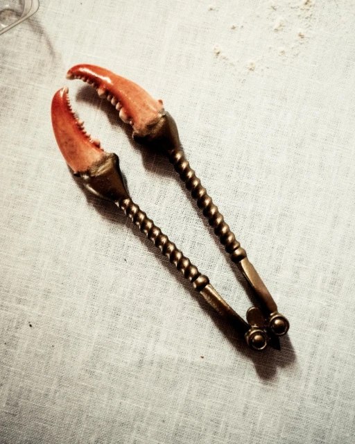 Macro shot of antique silver crab crackers on white linen, food and beverage, kitchen utensils. Perfect for food blogs and culinary websites.