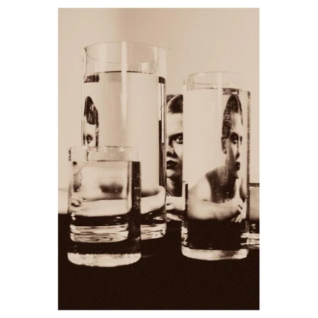 Monochrome photo of water glasses with distorted reflections of a person, creating a surreal and artistic visual statement.