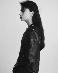 Black and white portrait of a woman in profile wearing a leather jacket against a light background