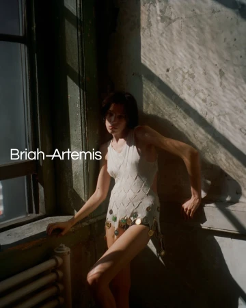 Woman in textured one-piece poses near window with textured walls, showcasing natural light and shadow in an indoor setting.
