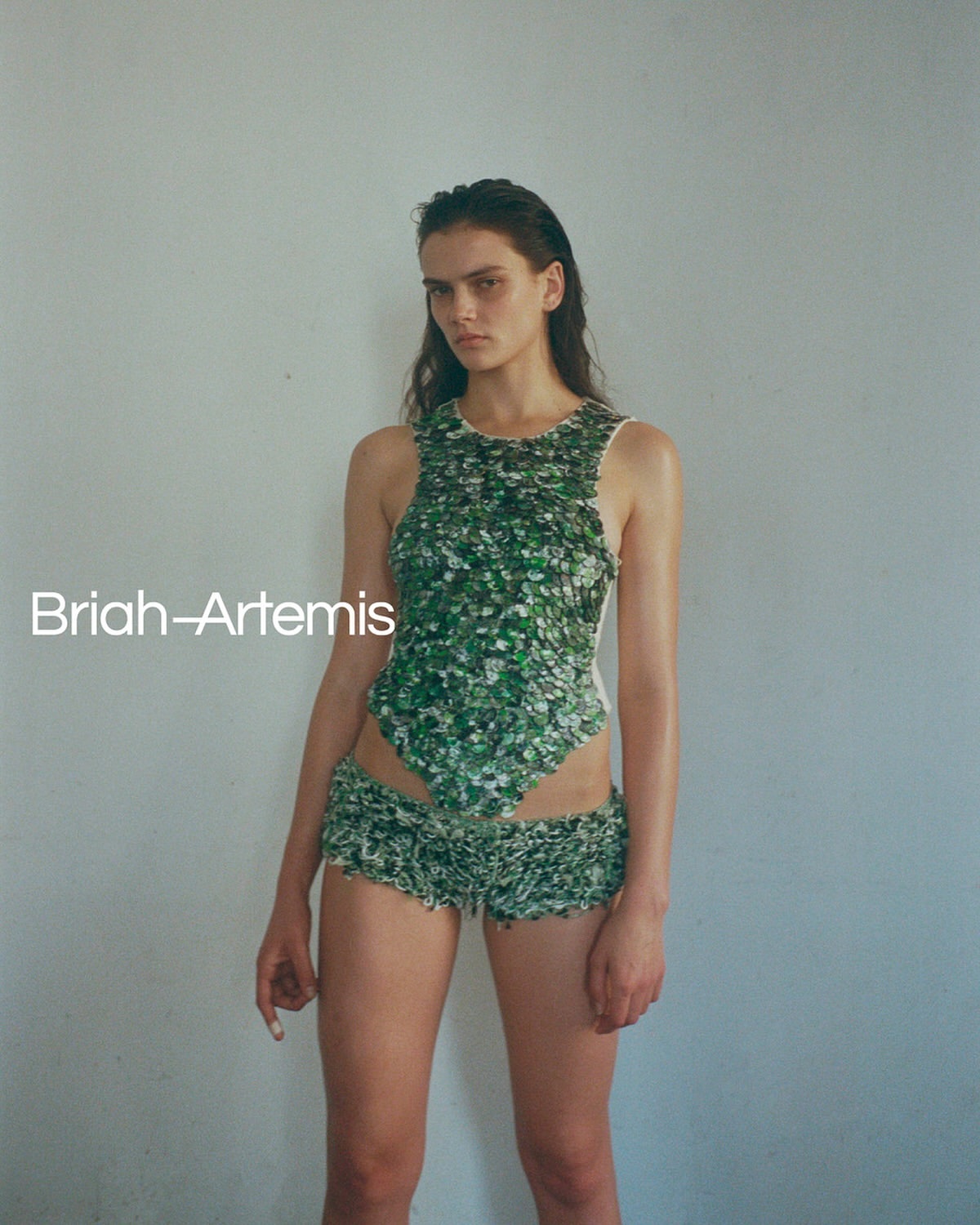 Portrait of a young woman in a floral-print two-piece outfit in front of a grey wall, fashion photography, beauty shot, natural light.