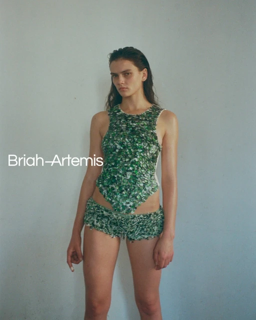 Portrait of a young woman in a floral-print two-piece outfit in front of a grey wall, fashion photography, beauty shot, natural light.