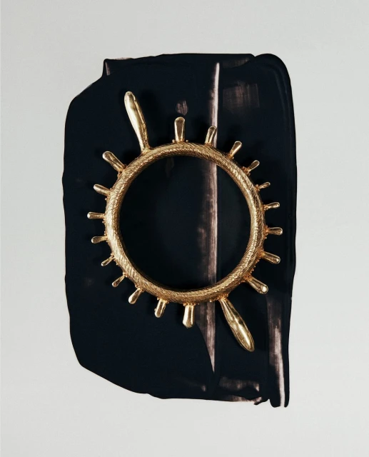 Abstract close-up of a gold ornamental ring against a black and white painted backdrop, showcasing texture and contrasting colors.