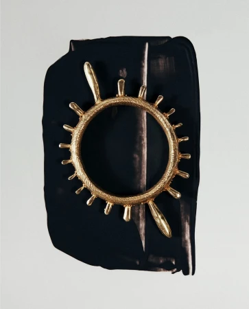 Abstract close-up of a gold ornamental ring against a black and white painted backdrop, showcasing texture and contrasting colors.