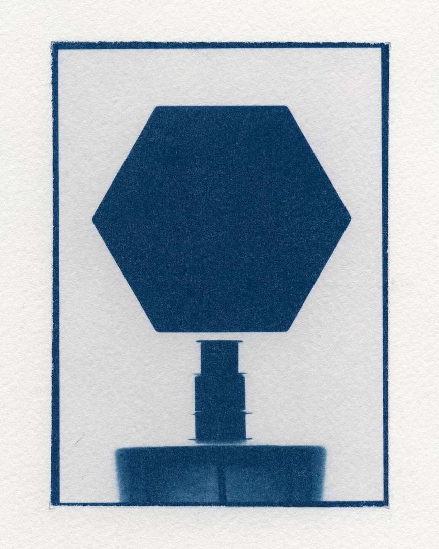 Abstract cyanotype image of a geometric, three-tiered, symmetrical object against a white background within a dark blue border.