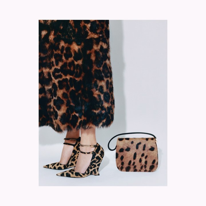 Ankle-strap wedge heels and a matching clutch purse with a leopard print pattern on a white background in a fashion product shot.
