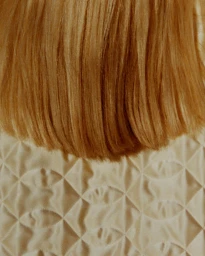 Close-up of straight blonde hair falling over a textured quilted fabric background by Jackie Kursel.