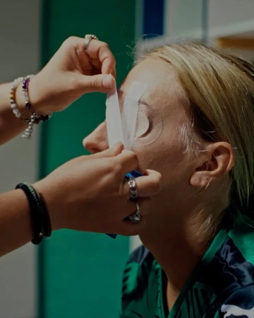 Woman receiving eye treatment at a beauty salon. Close-up of aesthetician applying white strips below eyes for lash or skin care service.