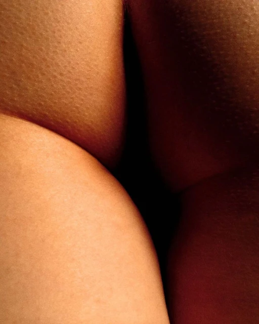 Macro close-up of human skin with warm lighting showcasing skin texture and color variations, set against a dark background.