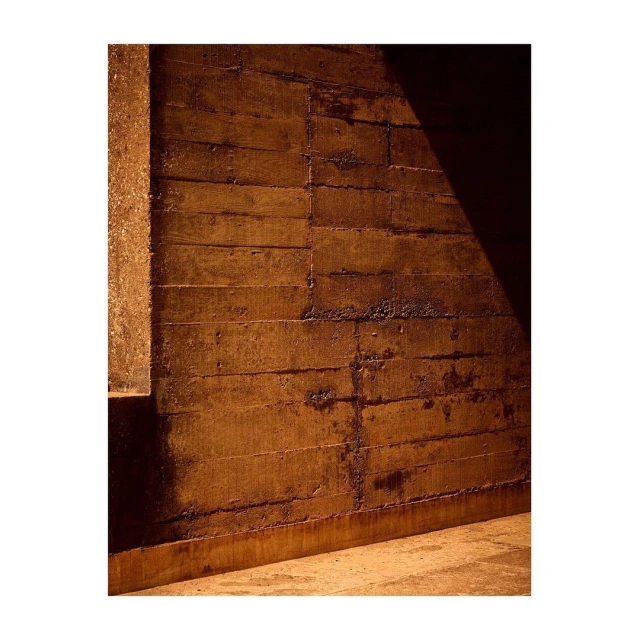 Abstract concrete wall with horizontal lines, partially illuminated by light from the right. Architectural textures and shadows.