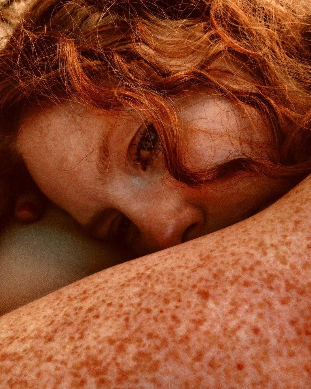 Close-up portrait of a fair-skinned woman with freckles and red hair, capturing a beauty shot with a shallow depth of field.
