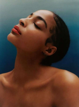 Close-up profile portrait of a woman with her head tilted back, wearing bright red lipstick against a moody gradient background