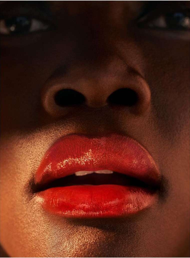 Close-up of a Black woman's face with glossy, red lips prominently displayed, emphasizing beauty and detail in skincare.